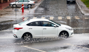 White,Car,Driving,Fast,On,Wet,City,Road,During,Rain,